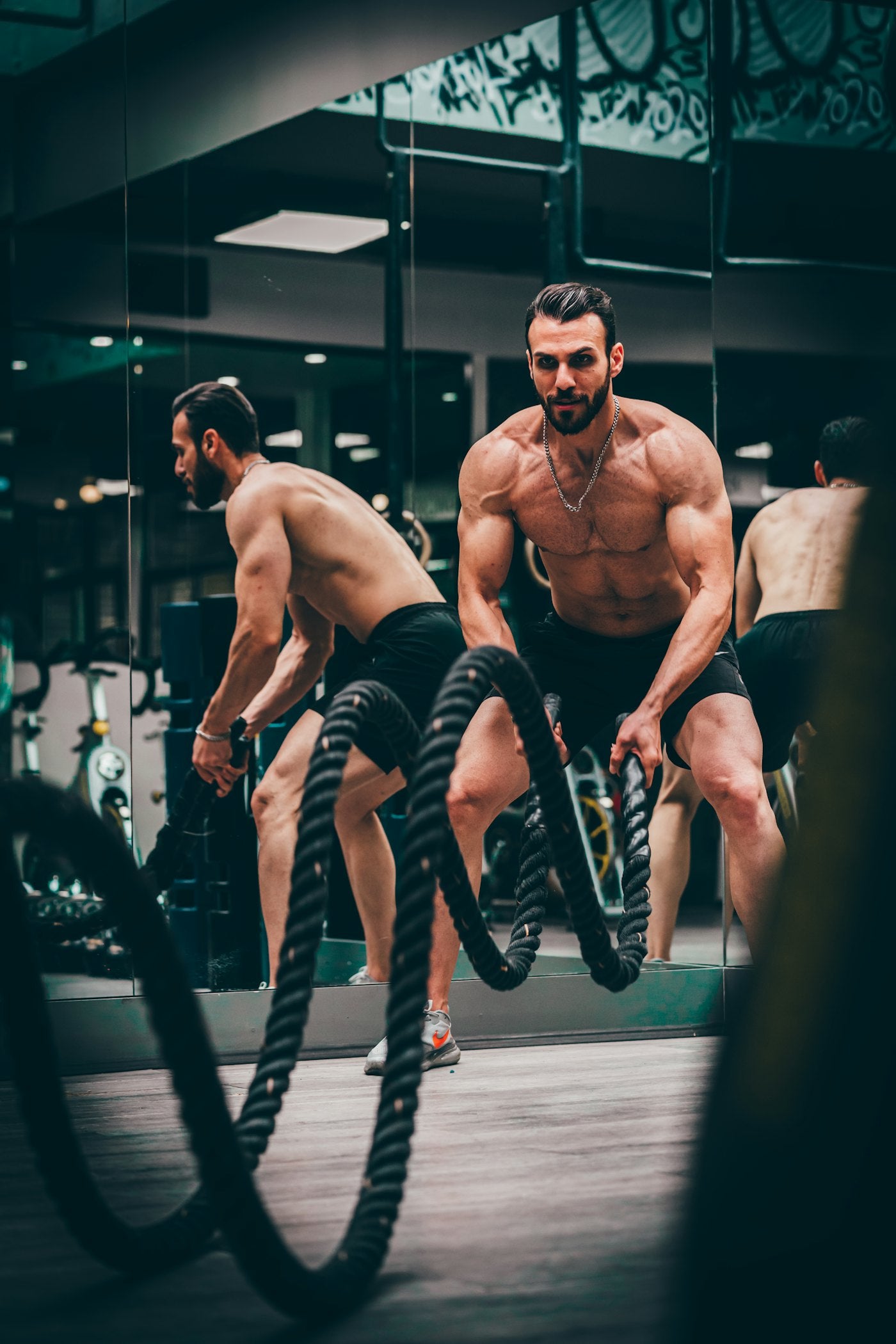 Athlete training with battle ropes in a dark gym